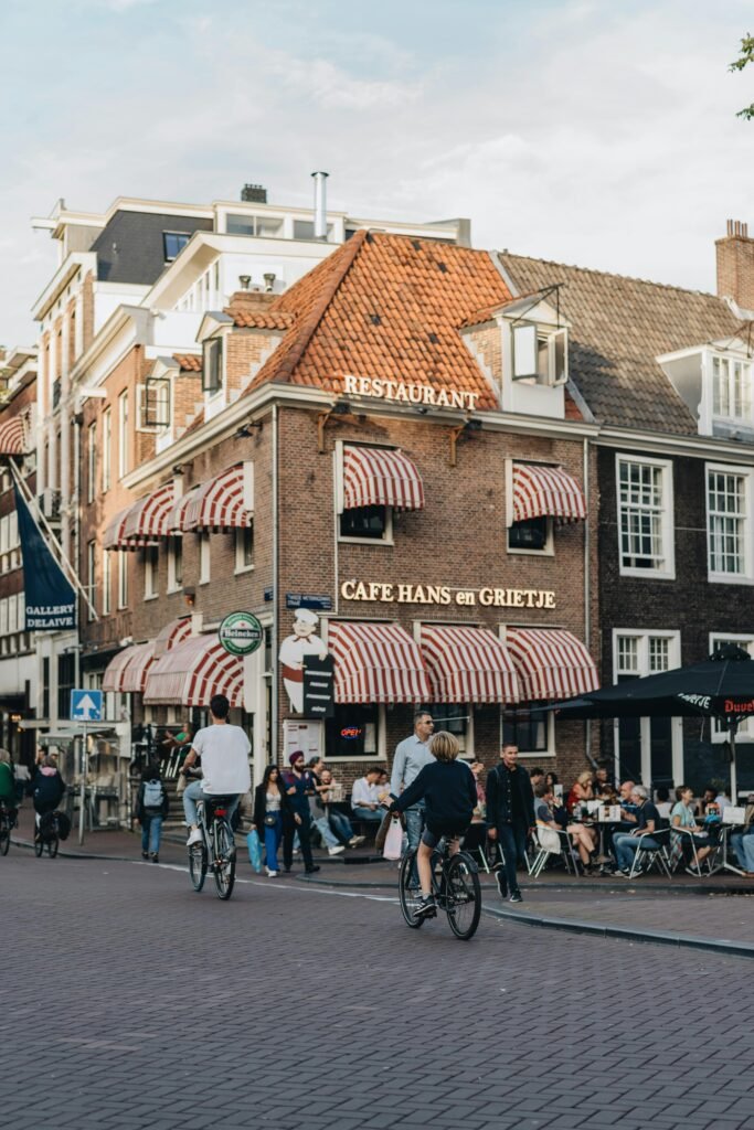 Visiter Amsterdam comme une locale à vélo devant un café typique.